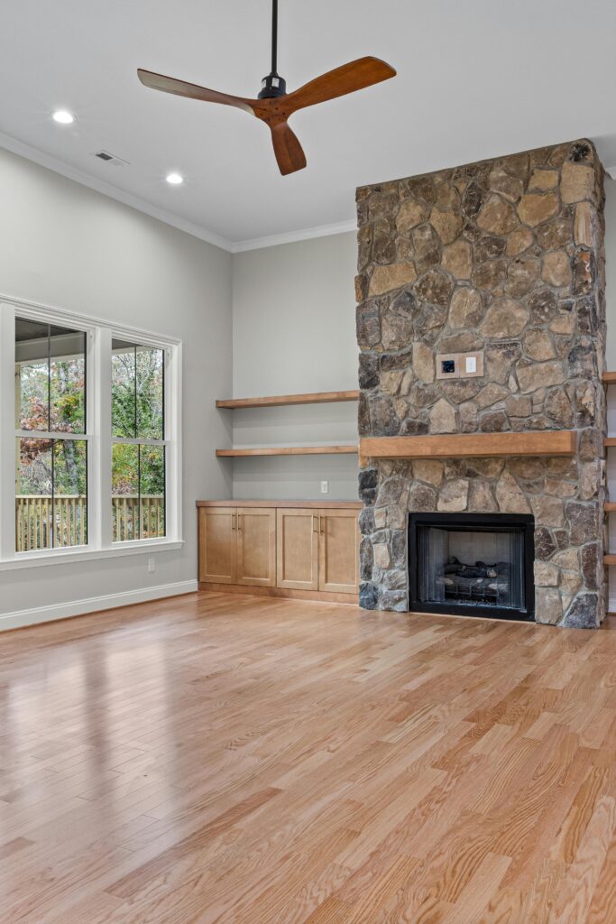 Contemporary living room interior featuring a stone fireplace and wooden flooring.